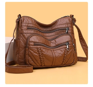 Detail of dark brown PU leather crossbody bag with multiple zippers and woven texture