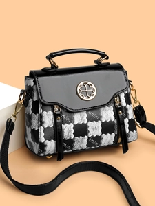 Detail view of the black and white pattern handbag with clover metal buckle