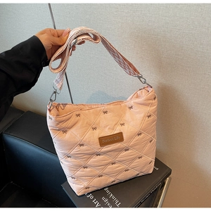Détail d'un sac cabas rose matelassé avec broderie nœud et bandoulière tissée