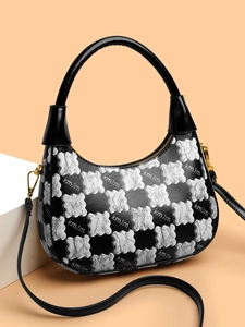 Detail of hobo bag with black and white floral pattern, gold hardware and leather handle
