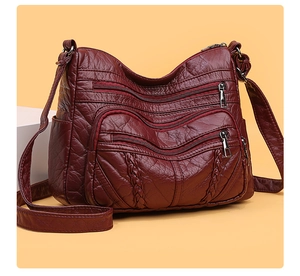 Detail view of dark red PU leather shoulder bag with multiple zippers and woven accents