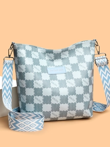 Détail d'un sac seau bleu clair avec motif monogramme et bandoulière tissée sur socle