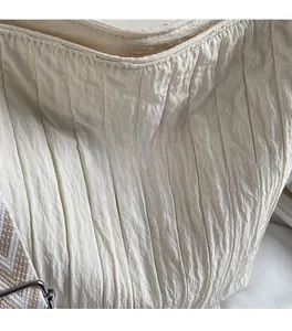 Détail du sac cabas en toile ivoire avec texture plissée et sangle à motif géométrique