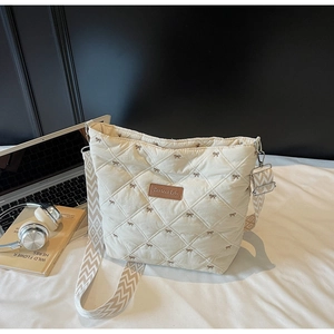 Détail du sac cabas beige matelassé avec broderies nœuds marrons et large bandoulière