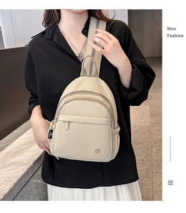 Close-up of stylish beige nylon sling bag with branded woven label and dual zippers