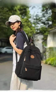Detailed view of a black corduroy backpack with leather pullers in an outdoor setting