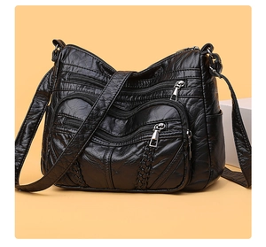 Detail of black pleated PU leather crossbody bag with woven trim and silver hardware