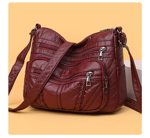 Close-up of wine red PU leather crossbody bag with woven texture and zipper detail