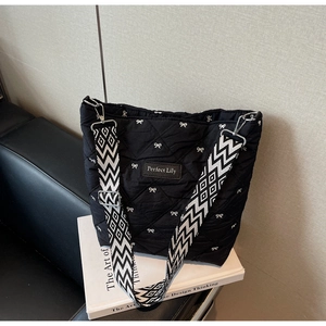 Détail du sac cabas matelassé noir avec broderie nœud blanc et sangle géométrique