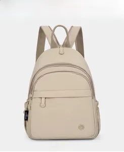 Detail view of beige nylon backpack featuring multi-layer zippers and embossed round logo