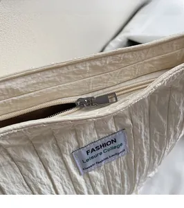 Gros plan sur la texture plissée beige du sac en toile avec zip métallique argenté