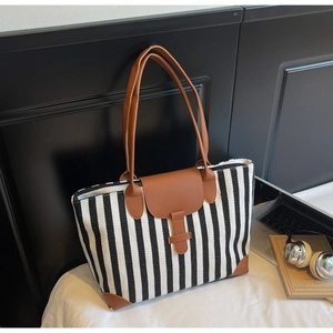 Detail of striped canvas tote bag showing reinforced leather handles and stitching