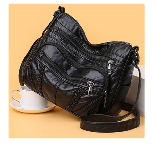Detail of black multi-pocket PU leather crossbody bag with pleated texture and zips