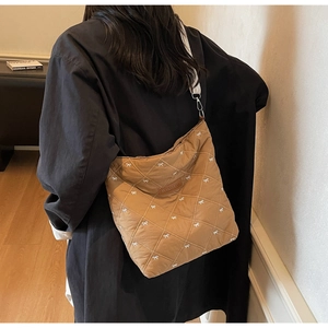 Détail d'un sac cabas marron matelassé avec broderies nœuds blancs et large sangle