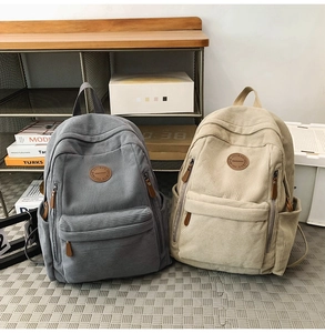 Detailed close-up of corduroy texture and leather logo on grey and beige backpacks
