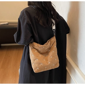 Détail du sac cabas matelassé marron avec broderie nœud et large bandoulière géométrique