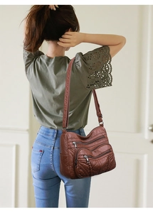 Detail of dark brown PU leather tote with multi-zipper texture on a shoulder strap