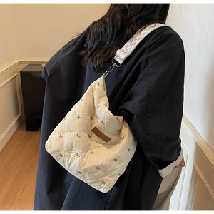 Détail du sac fourre-tout matelassé crème avec motifs de nœuds et large bandoulière tissée