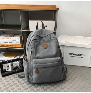 Detail view of grey corduroy backpack with leather logo patch and premium metal zippers
