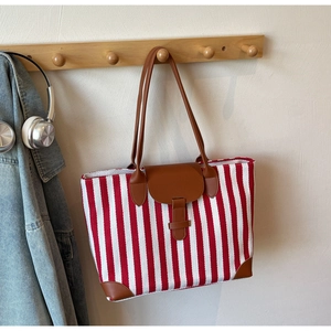 Detailed view of red and white striped canvas tote bag with brown leather trim details