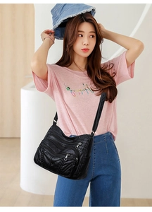 Detail of black PU leather crossbody bag with multiple zippers and woven side accents
