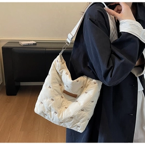 Détail du sac matelassé blanc avec broderie nœud et bandoulière géométrique tissée