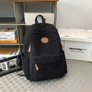 Detail of black corduroy backpack showing ribbed texture and vintage logo patch
