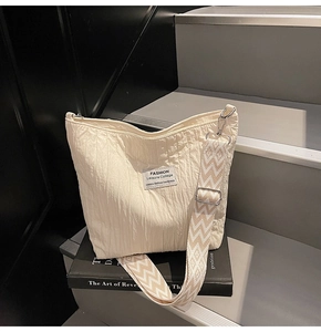 Détail d'un sac cabas plissé beige avec bandoulière à motif sur un livre d'art