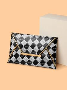 Détail de pochette enveloppe noire avec motif trèfle argenté et garniture dorée en V