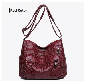 Detail of burgundy PU leather crossbody bag with three metal zippers and soft texture
