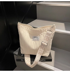 Détail du sac cabas en toile plissée crème avec large bandoulière à motifs géométriques