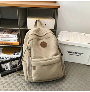 Detail of beige corduroy backpack showing soft texture and side pocket in home setting