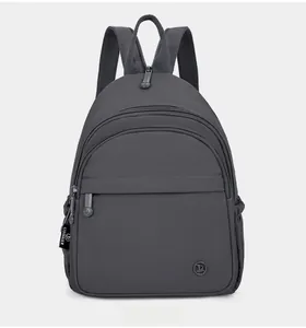 Front detail of dark grey mini backpack with tiered zipper pockets and wide straps