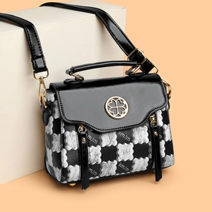 Chic black and white checkerboard handbag with golden clover lock and metal top handle