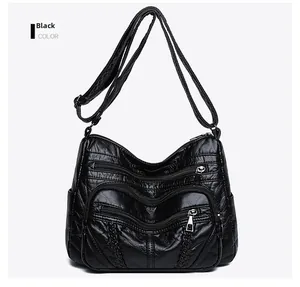 Close-up of black PU leather shoulder bag with multiple front zipper pockets and woven detail