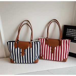 Detail of striped canvas tote bags with brown leather trim on white marble background