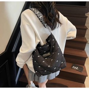 Détail du sac fourre-tout noir matelassé avec broderie nœud blanc et large bandoulière