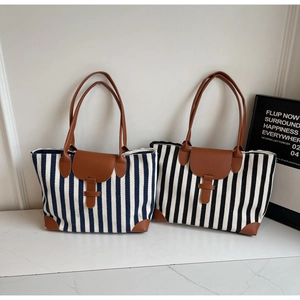 Detailed view of striped canvas tote bags with brown leather straps on marble surface
