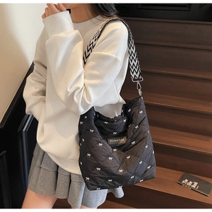 Détail du sac matelassé noir avec broderie nœud et bandoulière à motif zigzag élégante