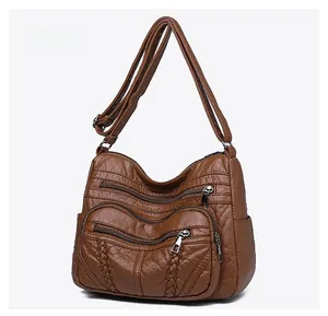 Detail view of brown PU leather crossbody bag featuring multiple zippers and woven accents