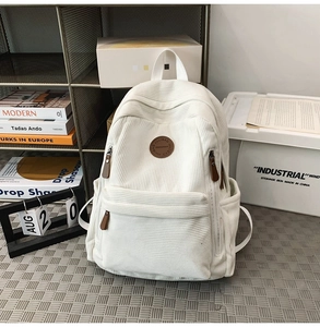 Detailed macro view of white corduroy backpack texture and round brown leather brand logo