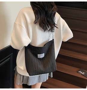 Détail du sac cabas en toile plissée noire avec bandoulière large en jacquard géométrique