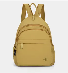 Front detail of ginger yellow nylon backpack featuring multiple zippers and woven handle