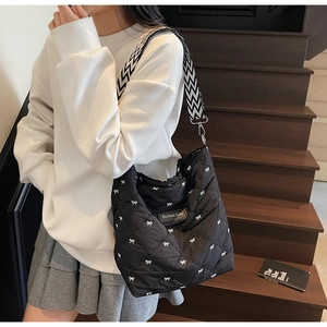 Détail du sac cabas matelassé avec motifs nœuds blancs et large bandoulière stylée