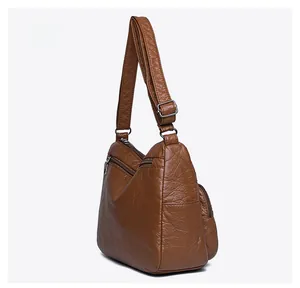 Side view detail of brown PU leather shoulder bag featuring multi-layer zippers and side pocket