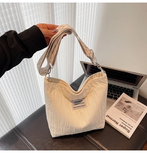 Détail du sac cabas en toile crème avec texture plissée et bandoulière géométrique