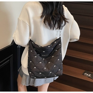 Détail du sac bandoulière matelassé noir avec broderies nœuds et sangle à motifs