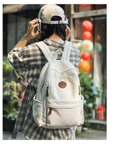 Outdoor view of large cream corduroy backpack with stylish leather brand logo and retro design