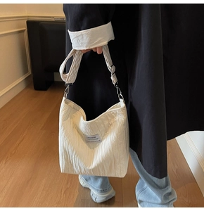 Détail du sac fourre-tout plissé en toile blanche avec bandoulière géométrique