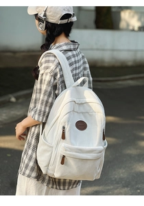 Detail of off-white corduroy backpack showing large capacity and brown leather logo tag